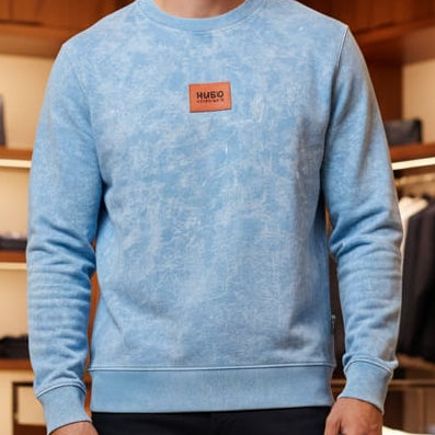 Man wearing a blue sweater with a logo in a clothing store