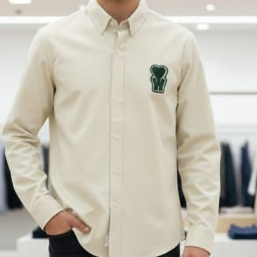 Man wearing a beige shirt with a logo in a clothing store