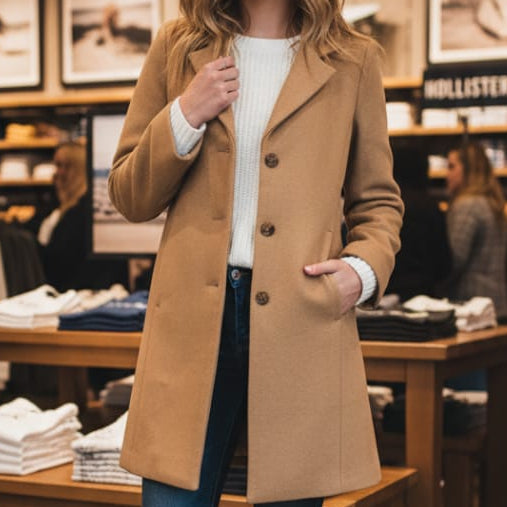 Woman wearing a tan coat in a clothing store
